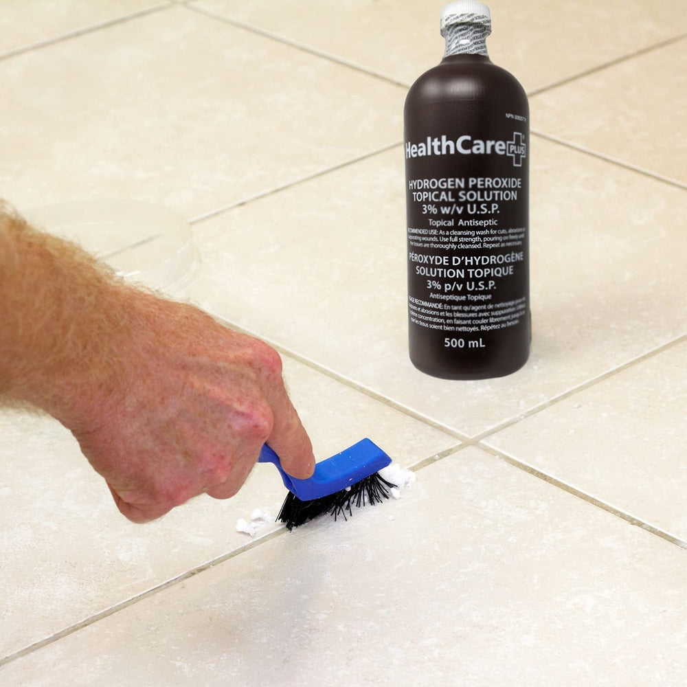 A boy is cleaning tiles with a brush, alongside a Healthcare Plus® Hydrogen Peroxide Topical Solution bottle